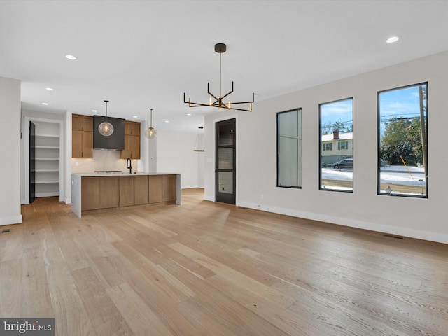 unfurnished living room with a chandelier and light wood-type flooring