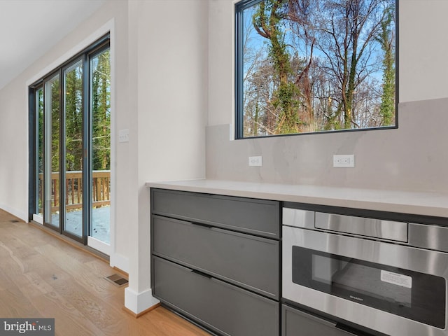 details featuring hardwood / wood-style floors, decorative backsplash, and stainless steel microwave