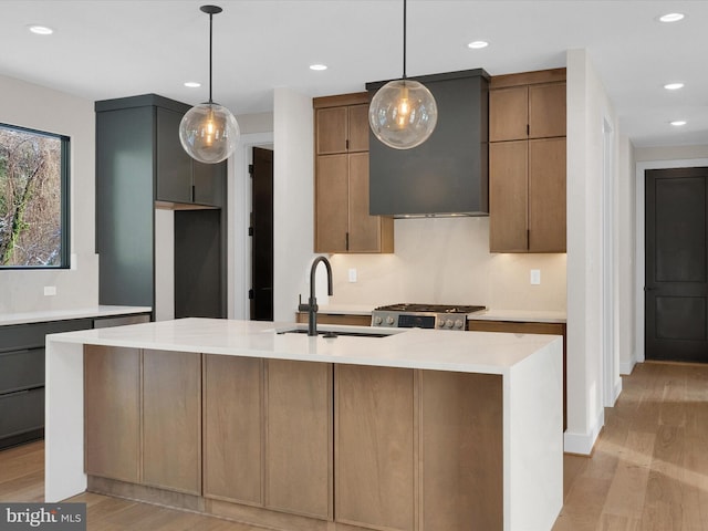 kitchen with sink, a kitchen island with sink, light hardwood / wood-style floors, and hanging light fixtures