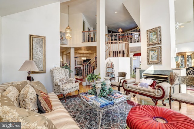 living room featuring a fireplace, hardwood / wood-style flooring, high vaulted ceiling, and ceiling fan