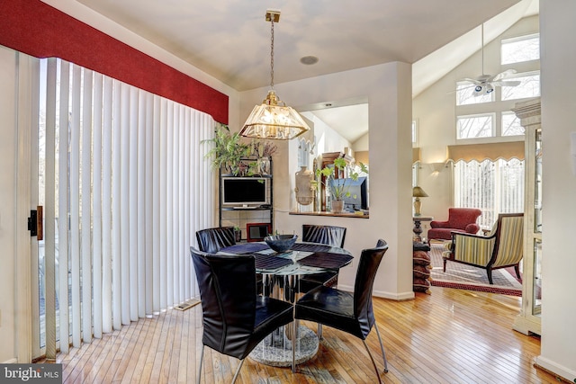 dining area featuring vaulted ceiling, hardwood / wood-style floors, and ceiling fan with notable chandelier