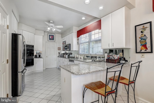 kitchen with white cabinets, ceiling fan, light stone counters, kitchen peninsula, and stainless steel appliances