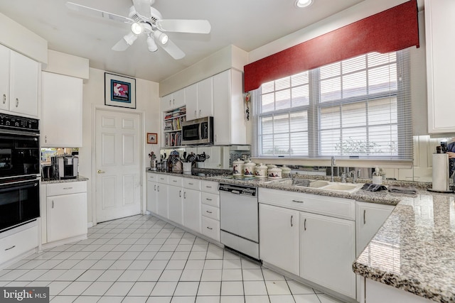 kitchen featuring dishwasher, sink, light stone counters, black double oven, and white cabinets