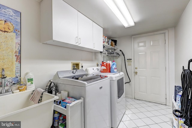 clothes washing area with light tile patterned flooring, cabinets, and washing machine and clothes dryer