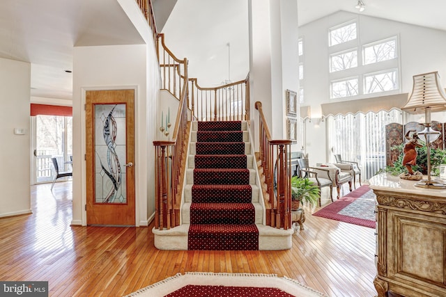 stairway featuring a towering ceiling, hardwood / wood-style flooring, and a wealth of natural light