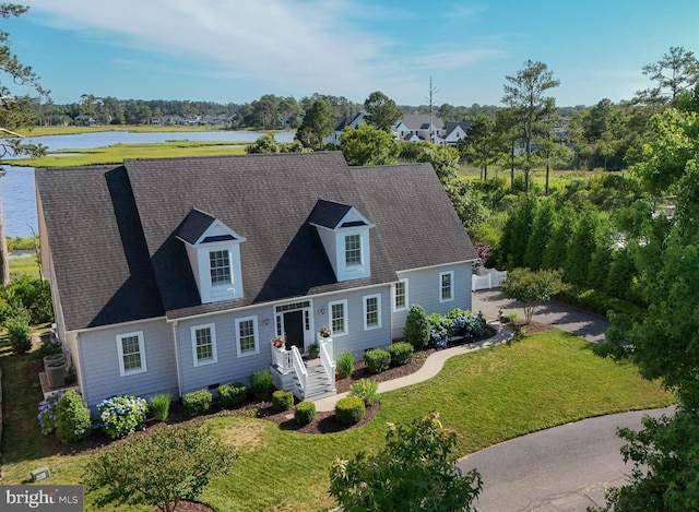 cape cod home with a water view and a front lawn