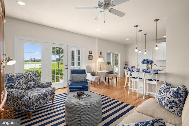 living room with ceiling fan, french doors, and light hardwood / wood-style floors