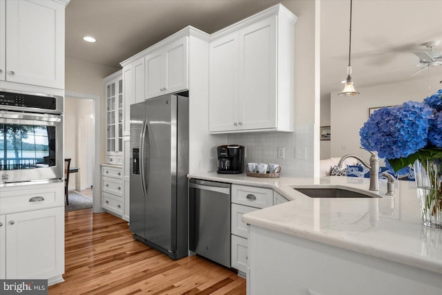 kitchen with tasteful backsplash, ceiling fan, sink, white cabinetry, and stainless steel appliances