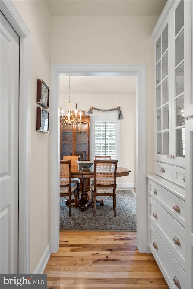 dining room with light wood-type flooring and an inviting chandelier