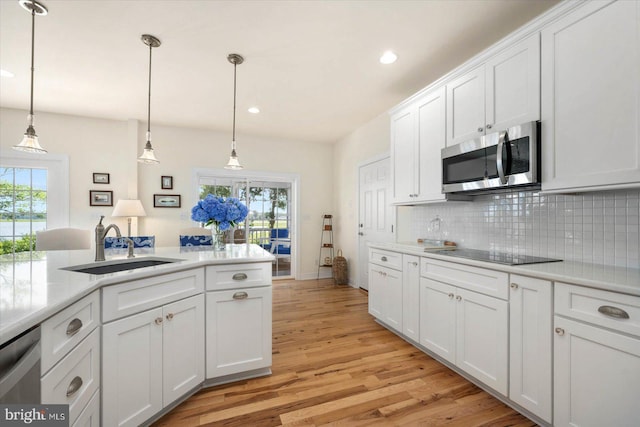 kitchen featuring appliances with stainless steel finishes, tasteful backsplash, hanging light fixtures, white cabinets, and sink