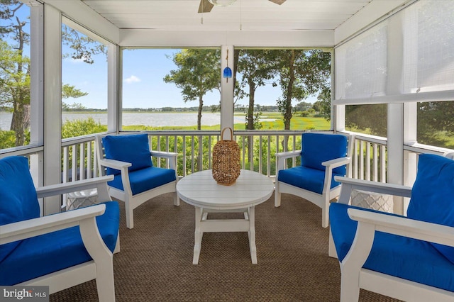 sunroom with ceiling fan, a wealth of natural light, and a water view