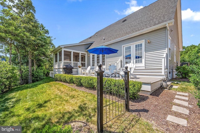 rear view of house featuring a patio area, a sunroom, and a lawn