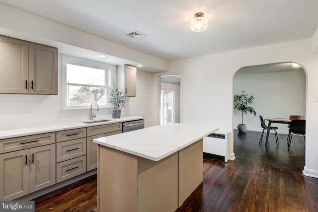 kitchen with dishwasher, radiator, decorative backsplash, a kitchen island, and sink