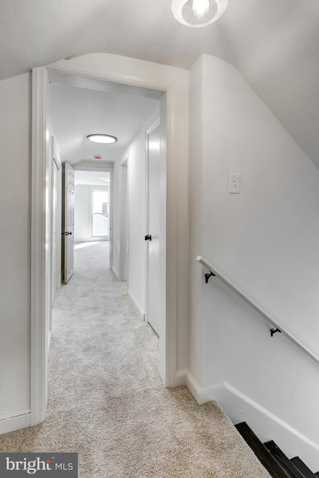 corridor featuring lofted ceiling and light colored carpet