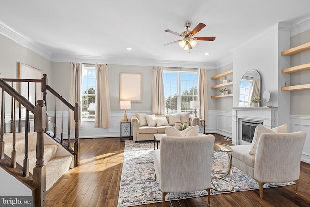 living room featuring built in features, plenty of natural light, crown molding, and dark hardwood / wood-style floors