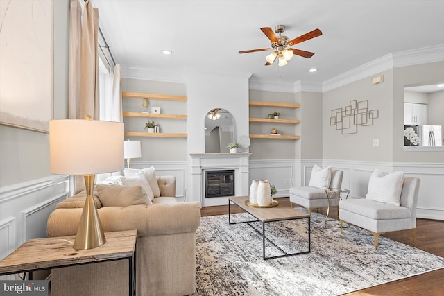 living room featuring ceiling fan, wood-type flooring, built in features, and crown molding