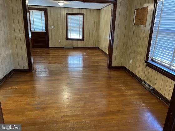 spare room featuring a wealth of natural light, wooden walls, and dark hardwood / wood-style flooring