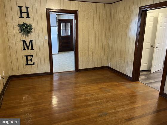 unfurnished room featuring wooden walls and dark hardwood / wood-style floors