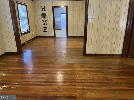 unfurnished room featuring wood walls and dark hardwood / wood-style floors