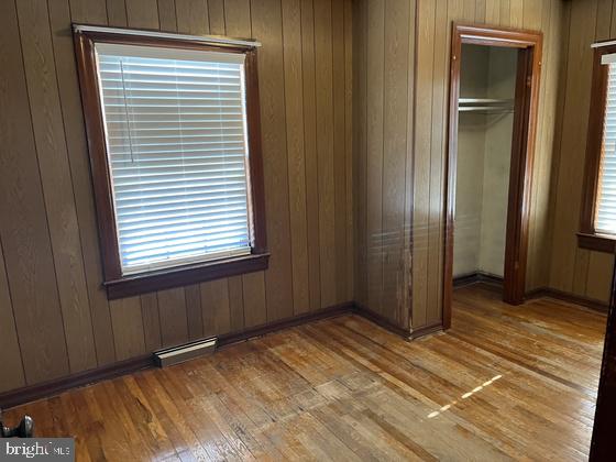 unfurnished bedroom with hardwood / wood-style flooring, wood walls, and a closet