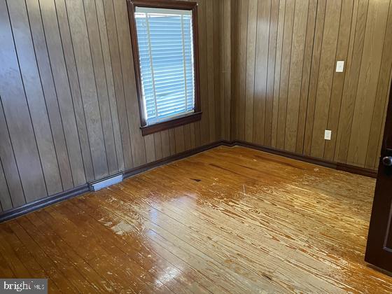 spare room with light wood-type flooring and wooden walls