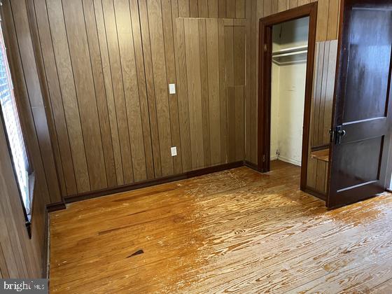 unfurnished bedroom featuring a closet, wood walls, and light hardwood / wood-style floors