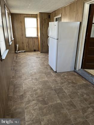 kitchen featuring white fridge and wood walls