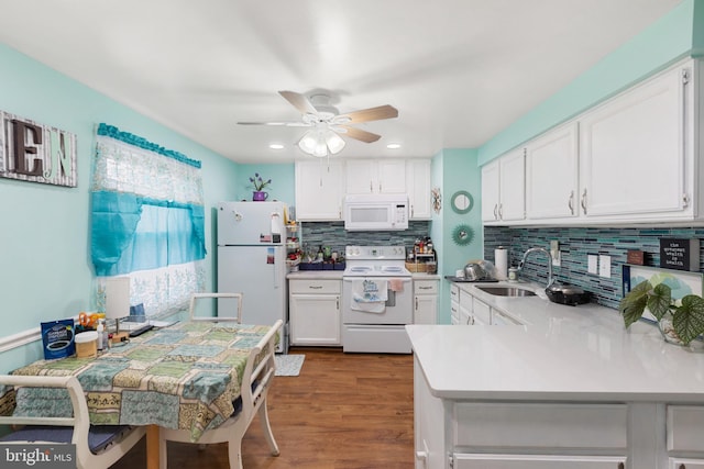 kitchen with white appliances, sink, kitchen peninsula, white cabinets, and tasteful backsplash