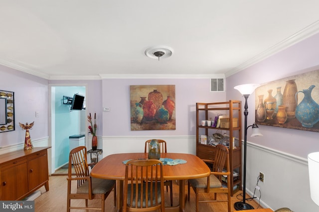 dining room with light wood-type flooring and crown molding