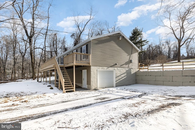 snow covered rear of property with a garage and a deck