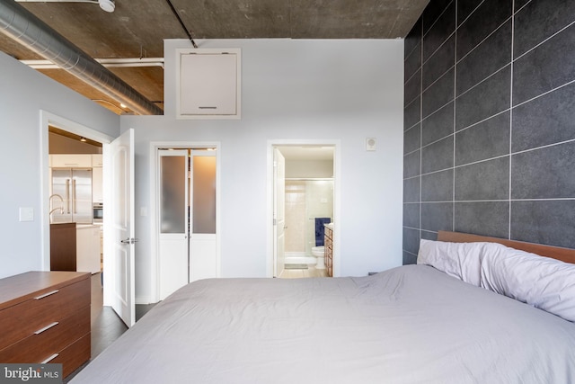 bedroom featuring connected bathroom and tile walls