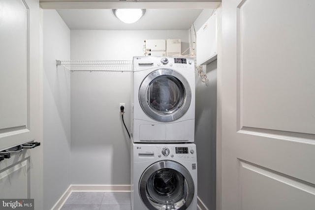 washroom featuring stacked washer and dryer and light tile patterned floors