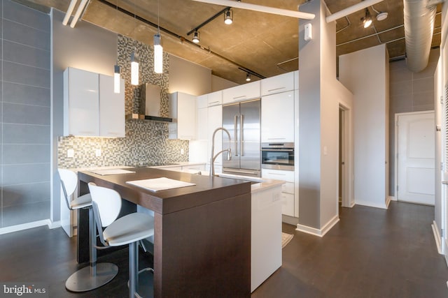 kitchen with a high ceiling, appliances with stainless steel finishes, pendant lighting, and white cabinets