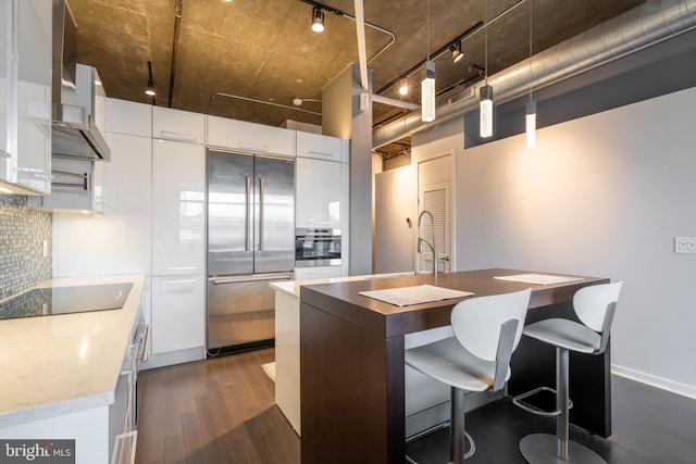 kitchen featuring white cabinetry, stainless steel appliances, track lighting, decorative backsplash, and wall chimney exhaust hood