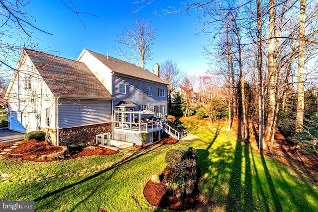 rear view of property with a yard, a sunroom, and a deck