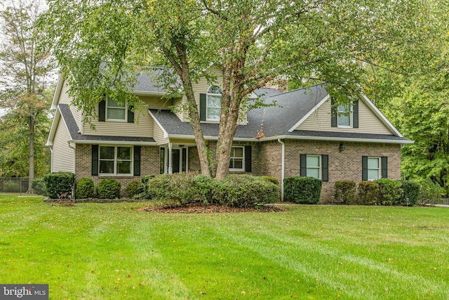 view of front facade featuring brick siding, roof with shingles, and a front yard