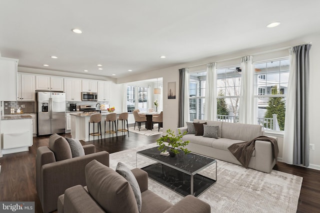 living room featuring sink, dark hardwood / wood-style flooring, and plenty of natural light