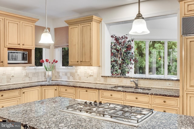 kitchen with appliances with stainless steel finishes, pendant lighting, a sink, and decorative backsplash