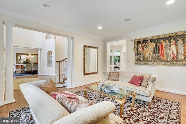 living area featuring crown molding, ornate columns, and wood finished floors