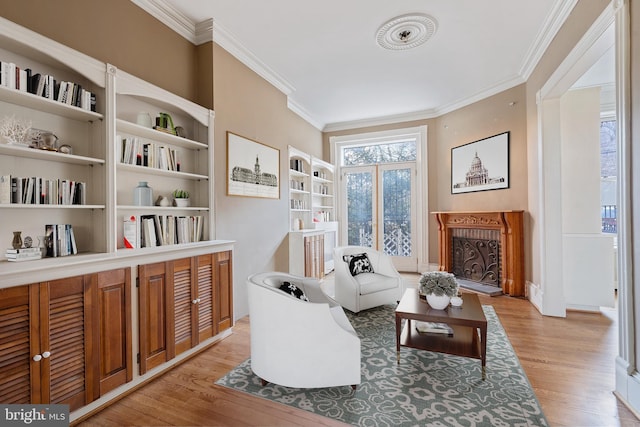 living area featuring crown molding, light hardwood / wood-style floors, and built in shelves