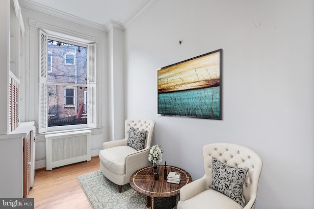 sitting room featuring a wealth of natural light, radiator, ornamental molding, and light hardwood / wood-style flooring