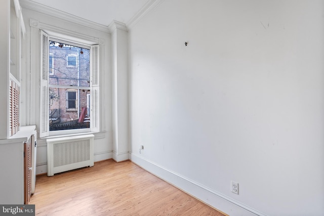 empty room featuring light hardwood / wood-style flooring, radiator heating unit, and crown molding