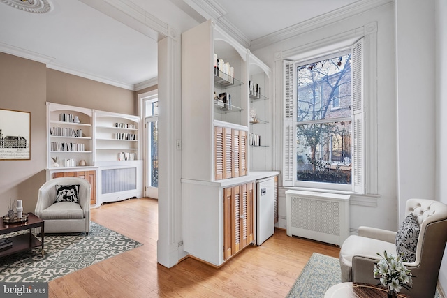 sitting room featuring radiator heating unit, ornamental molding, and light hardwood / wood-style flooring