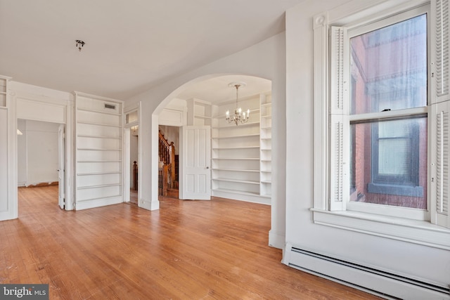 interior space featuring a baseboard heating unit, built in features, a chandelier, and light wood-type flooring