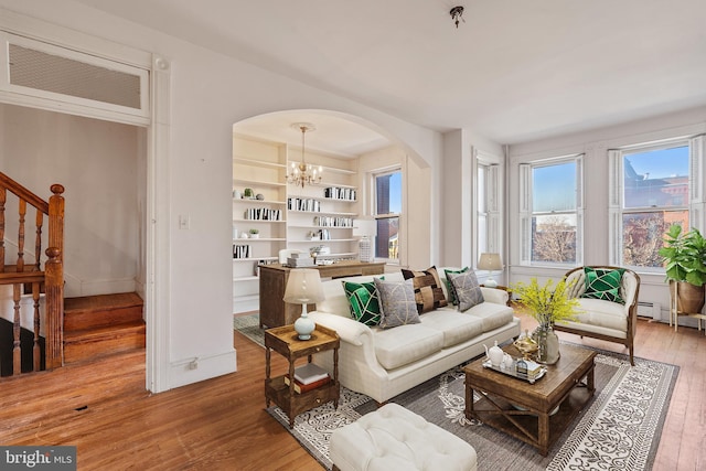 living room featuring hardwood / wood-style flooring, built in features, and an inviting chandelier