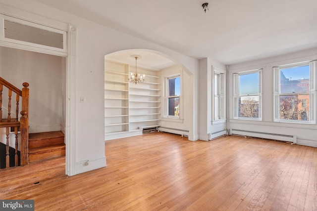 living room with built in features, light hardwood / wood-style flooring, a baseboard radiator, and an inviting chandelier