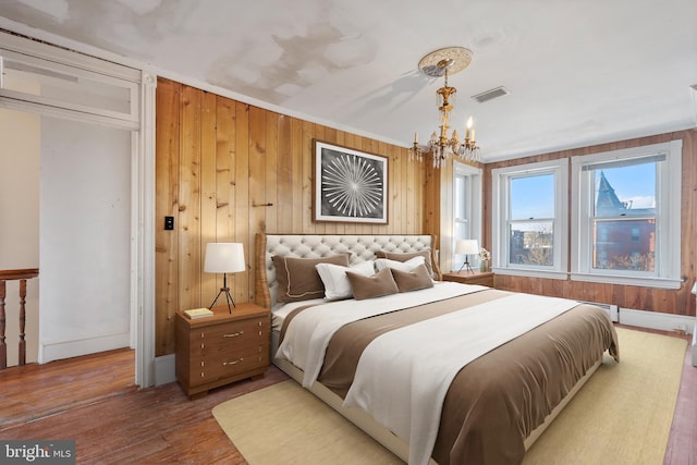 bedroom featuring a chandelier, crown molding, baseboard heating, and wood-type flooring