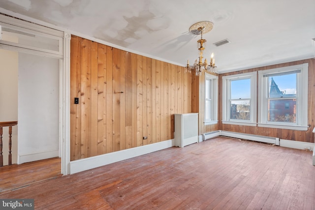 unfurnished room with hardwood / wood-style flooring, a baseboard radiator, crown molding, and a notable chandelier