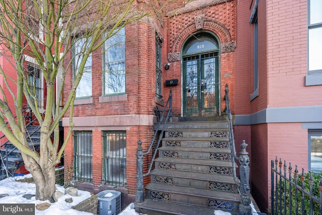 snow covered property entrance featuring central AC