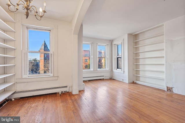 unfurnished living room with a baseboard radiator, hardwood / wood-style flooring, a chandelier, and built in features